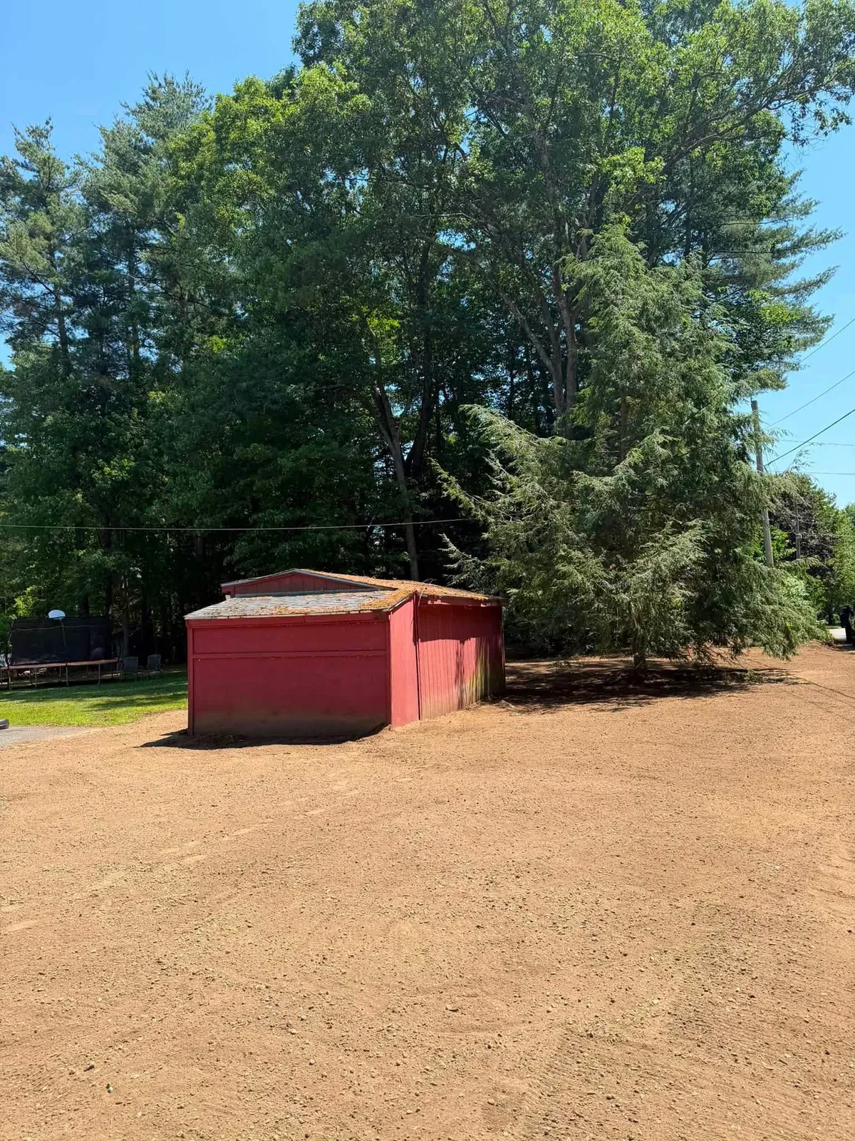 Large yard cleared and graded smooth beside a red shed