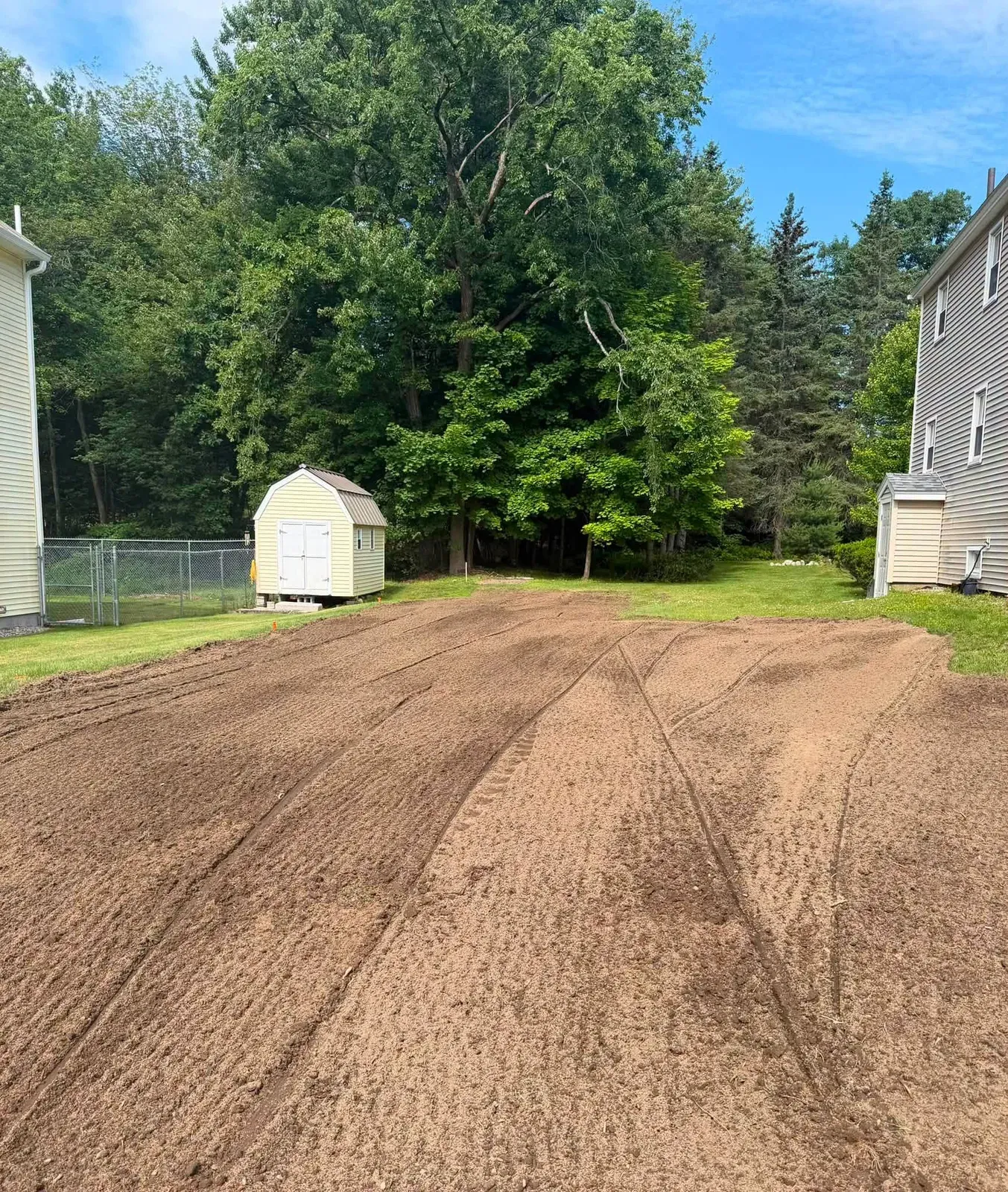 Backyard graded smooth between two houses with a shed in the back