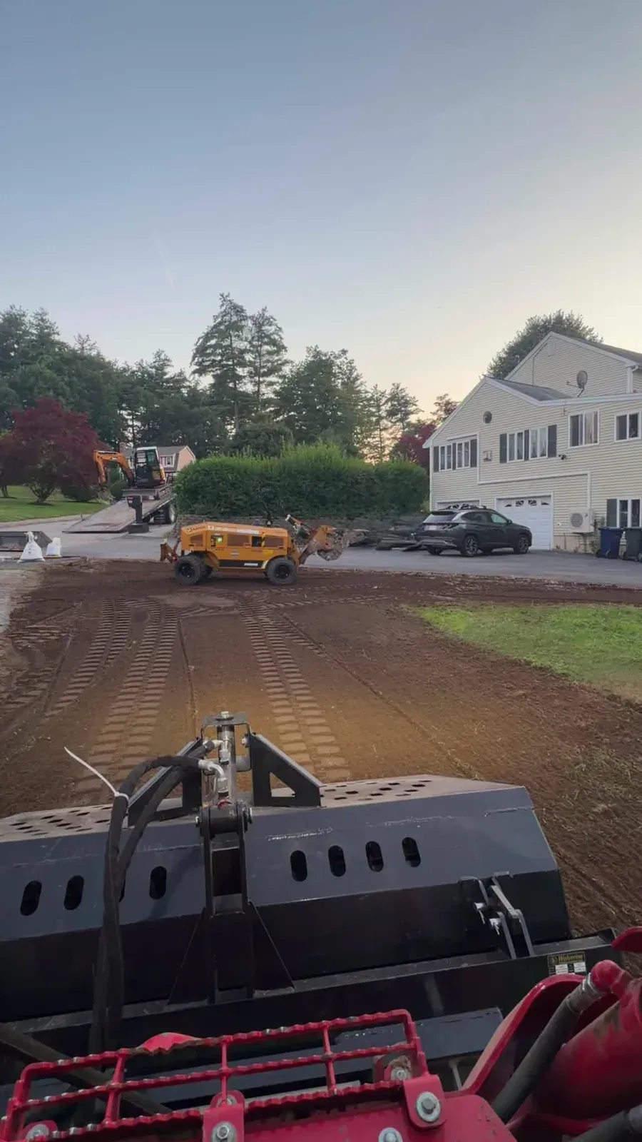 Grading a residential lot at dusk, seen from the loader seat