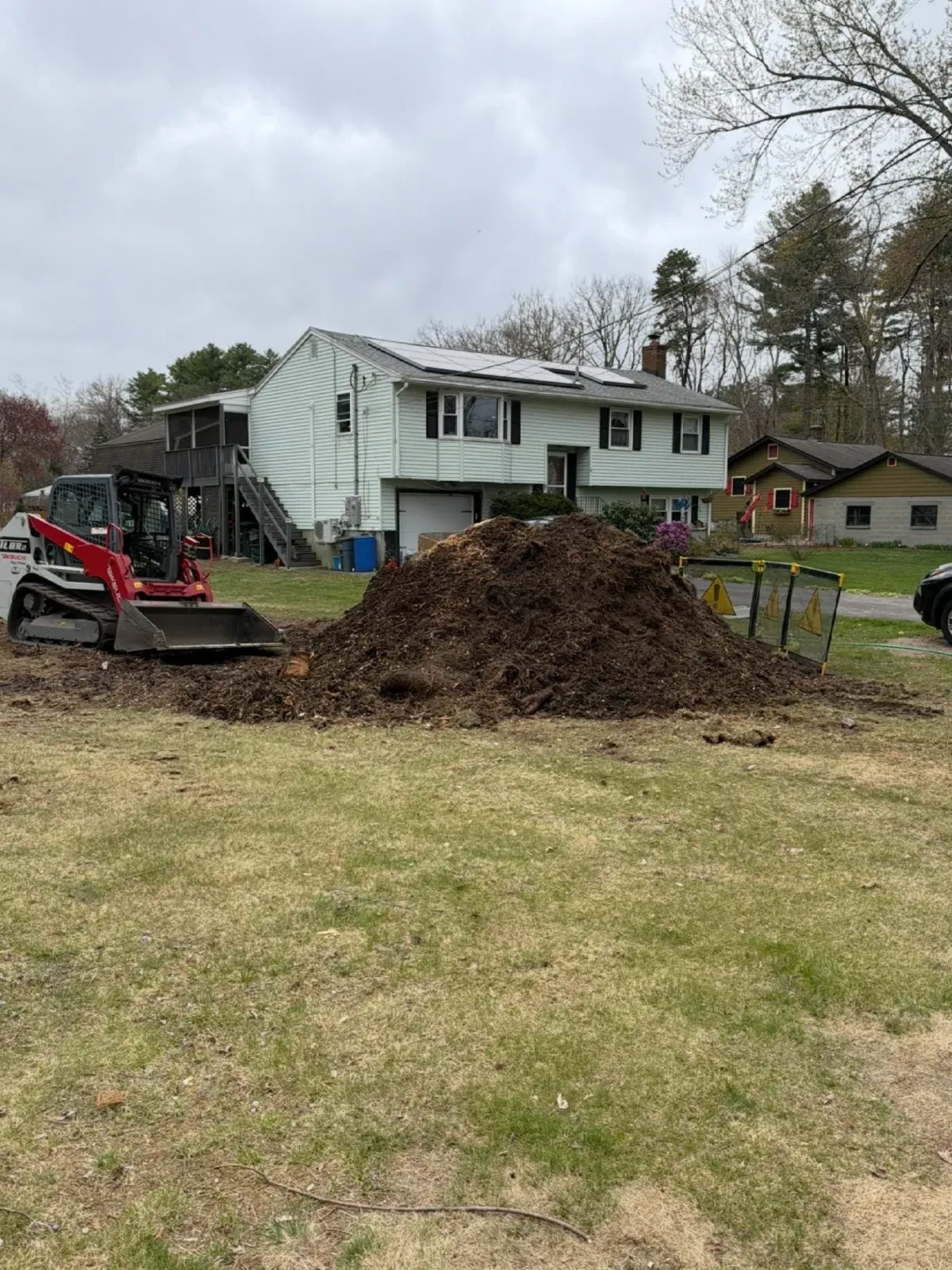 Track loader and a pile of soil in a front yard during site prep